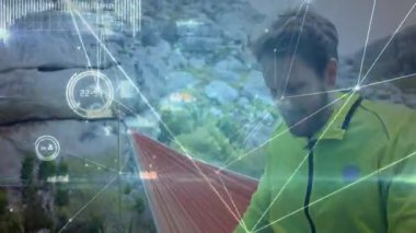 Orta yaşlı bir adam kaya yüzeyindeki hamağı emniyete alıyor teknolojik kaplamayı başlatıyor ve rahatlamaya yöneliyor. Macera, açık hava, dirençli, sükunet, teknoloji, keşif, dayanıklı