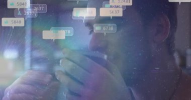 Kafede kahve fincanı kaldıran sosyal medya ikonlarını yudumlayan ve artan sayıları sayan bir adam. Gündelik, rahatlatıcı, modern, dijital, iç mekan, boş zaman, tefekkür.