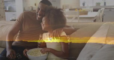 Babası uzaktan kumandayla kanal değiştirirken, kızı da ev eğlencesi için kanepede patlamış mısır yiyordu. Aile, rahatlama, bağlanma, rahatlık, rahatlık, modern, rahat