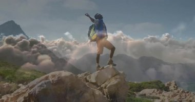 Zirveye ulaşan erkek yürüyüşçü kaya parçasına ayak basıyor ve seyahat bulutu manzarasını kutlarken kollarını kaldırıyor. Macera, başarı, vahşi doğa, keşif, panoramik, kararlılık, açık hava