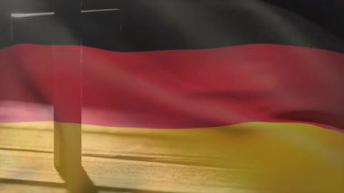 Metal direğe asılmış Alman bayrağı meltemle dalgalanarak ahşap zemine gölge düşürüyor. Vatanseverlik, milliyetçilik, açık hava, kumaş, hareket, sükunet, sembolizm