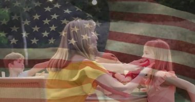 Anne teras masasından peçete alıyor ve ebeveynlik hijyeni için kızının ağzını nazikçe siliyor. Aile, yetiştirme, şefkat, açık hava, boş zaman, samimiyet, yaşam tarzı