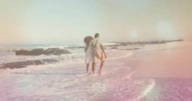 Islak kumda yürüyen bir çift sörf yaparken beyaz elbiseler içinde seyahat reklamı yapıyor. Romantizm, dinginlik, rahatlık, macera, yaşam tarzı, doğal, canlı