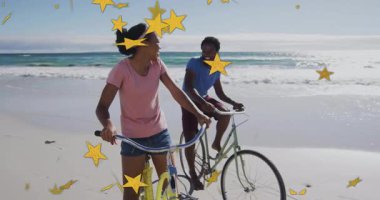 Bir çift, kum üzerinde bisiklet sürerek hareket eden yıldız şekilleri etrafında dönerek seyahati kutluyor. Romantizm, macera, dinginlik, canlı, eğlenceli, boş zaman, bağlantı