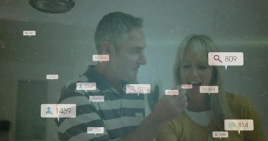 Olgun bir adam ev mutfağında kadınları beslerken veri baloncukları pazarlama hızını arttırıyor. Çift, katılım, dijital, modern, bağlantı, samimiyet, teknoloji