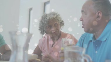 Son sınıf çifti camla konuşuyor. Sürüklenen bokeh ışıkları yakıyor. Yaşam tarzı sıcaklığı ekliyor. Emekliler, samimiyet, arkadaşlık, sıcak ışıklandırma, evcil sahne, sevgi, rahatlama.