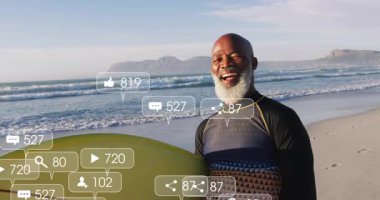 Olgun erkek sörfçü elinde sosyal simgelerle gülerek nişan güncellemesi yapıyor. Macera, açık hava, eğlence, motivasyon, kıyı, enerji, bağlantı