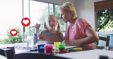 Çocuk daldırma fırçası, sanat eğitimi için yüzen kalplerle rehberlik eden anneyi tetikler. Ebeveynlik, yaratıcılık, bağlanma, eğitim, sevgi, suluboya, ev