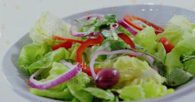 Bir saniye sonra, veri grafikleri zayıflıyor ve salata tabağında hareketleniyor, besinleri vurguluyor. Taze ürün, dijital arayüz, sağlık teknolojisi, beslenme analizi, aşçılık, modern tasarım, temiz mutfak
