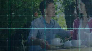 Kadın konukseverlik bahçesinde çaydanlıktan çay doldururken, erkek çay fincanına uzanıyor. Romantik, samimiyet, rahatlık, zarafet, sükunet, çiçek açma, doğa.