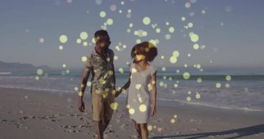 Kıyıda yürüyen çift, hayat tarzı romantizmi ve deniz kenarı öpücüğünü simgeleyen altın bokeh örtüsüyle. Romantizm, sükunet, açık hava, ahenk, sevgi, rahatlık, samimiyet.