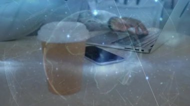 İş kullanıcısı kahveyle el ele verip sonra da dönen dünya ve ağ örtüsü ile dizüstü bilgisayarda yazı yazıyor. Teknoloji, uzaktan çalışma, üretkenlik, dijital bağlantı, modern çalışma alanı, yenilik, şirket