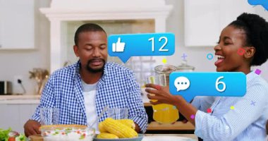 Anne meyva suyu döker, baba kızına bardak uzatır, sosyal medya simgeleri yüzer. Aile, ev, beslenme, birliktelik, yaşam tarzı, dijital, toplum