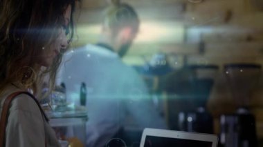 Barista 'nın bardağı yerleştirmesi, kadının kahvesini yudumlamasına ve kaldırmasına neden olurken teknik grafiklerin lezzet göstermesi. Kafe, iş istasyonu, minimalist, içecek, konukseverlik, sıcak, modernite.