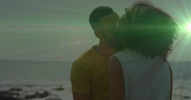 Gün batımında kumsalda bir kadınla göz teması kuran bir adam eğitim için yeşil lensler parlarken. Romantik, bağlantı, samimiyet, doğa, dinginlik, sıcaklık, şefkat