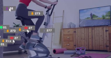 Gidonu çeken, pedal çeviren, bisiklet izleme fitness ölçümleri etrafında medya simgeleri üreten bir kadın. Fitness, angajman, dijital, motivasyon, spor salonu, etkinlik, modern