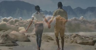 Kayalık sahilde yürüyen gezgin çift bulutları dağlara doğru sürüklerken. Macera, romantizm, sükunet, manzara, uyum, keşif, sükunet