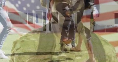 Aile teknolojik övgü için futbol topu sallarken asker miğferinin bayrak kaplamasını gösteriyor. Vatanseverlik, birlik, toplum, esneklik, aile, açık hava, boş zaman