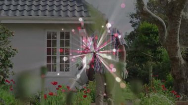 Kıdemli adam çerçeveye giriyor ve metal teneke kutuları eğiyor, kırmızı gelincikleri bahçe bakımı için suluyor. Bahçıvanlık, bahçıvanlık, çiçek, manzara, açık hava, sükunet, gelenek.