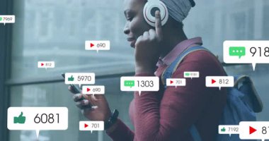 Kafasına sarkan telefon takan kadın cam korkuluklardan süzülen sosyal medya ölçümlerini izliyor. Teknoloji, şehir, yaşam tarzı, modern, iletişim, bağlantı, canlı