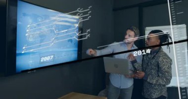 İki analist dizüstü bilgisayara bağlanıyor ve dijital haritayı işaret ediyor. Teknolojik trend analizi için zaman çizelgesini ayarlıyorlar. Teknoloji, işbirliği, fütürizm, veri görselleştirme, kurumsal, profesyonel, yenilik