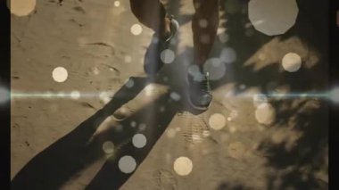 Koşucunun sağ ayağı kum ile temas ediyor. Koşu sırasında bokeh sürükleniyor ve lens parlıyor. Atletizm, açık hava, minimalist, hareket, enerji, doğa, teknik