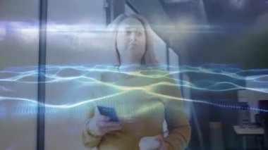 Akıllı telefonları dinleyen, mesajları kontrol eden ve teknoloji ofisinde dalga etkisi yaratan bir kadın. Modern, profesyonel, gösterişli, canlı, işbirlikçi, dinamik, yenilikçi