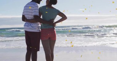 Sahile gelen çift, kıyıya adım atıyor ve altın yıldızların ortasında kol paylaşımı anı yaşıyor. Romantik, günbatımı, dinginlik, ufuk, şefkat, boş zaman, doğal