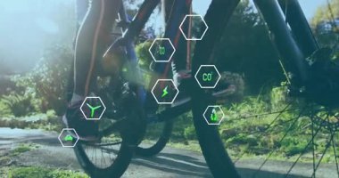 Bisikletçi, güneş ışığı altındaki park yolunda pedal çeviriyor, karbondioksit tasarruflarını gösteren neon yeşil eko-ikonları etkinleştiriyor. Macera, açık hava, çevre dostu, fitness, yenilik, sürdürülebilirlik, teknoloji