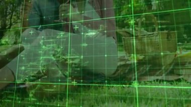 Piknikte çift üzerinde yeşil şebeke görünüyor ve teknoloji gösteriminde şarap kadehinin hareketlerini haritalıyor. Romantizm, samimiyet, kutlama, eğlence, açık hava, sükunet, bağlantı