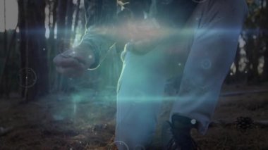 Çam iğneleri arasında sarı kollu cıvata gören ve avlanmak için arbalet yerleştiren bir adam. Okçuluk, avcılık, açık hava, vahşi doğa, hassasiyet, doğa, kamuflaj.