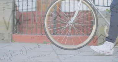 Kaldırımda bisiklet tekerine binen bir kadın eğitim denklemleriyle bisiklet sürerek dönüşüme sebep oluyor. Kentsel, fitness, motion, modern, teknoloji, motivasyon, ilerleme