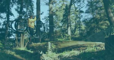 Bisikletçi, devrilen ağacın yanında orman yolunu kapatıyor, bisikleti kaldırıyor ve kütüklerin üzerinde dengede duruyor. Macera, açık hava, dayanıklılık, mücadele, keşif, aktivite, dayanıklılık