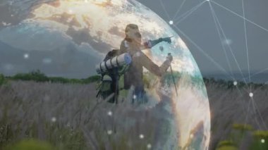 Yürüyüşçüler çayırda ileri adım atıyorlar. Dönen dijital küreyi çalıştırıyorlar. Teknoloji haritası için veri topluyorlar. Macera, keşif, bağlantı, teknoloji, açık hava, manzara, takım çalışması