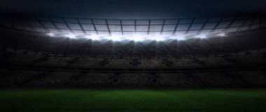 Stadyum projektörlerin altında yeşil alan, karanlık stantlar ve çatı kirişleriyle parıldıyor. Spor, arena, ikon, aydınlatma, mimari, boş zaman, açık hava