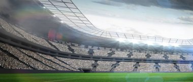 Çim sahası, katmanlı tribünler ve güneş ışığını filtreleyen çatılı paneller gösteren stadyum. Spor, altyapı, mimari, yaşam tarzı, açık hava, modern, rekabet