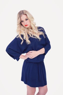 Beyaz arka planda dikilirken gözlerini kaçıran genç kadın.