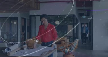 Tasarımcı ofiste planlar üzerinde çalışıyor, yönetici tabletle yürüyor ve yol gösteriyor. İşbirliği, mimarlık, planlama, profesyonel, yenilik, takım çalışması, modern