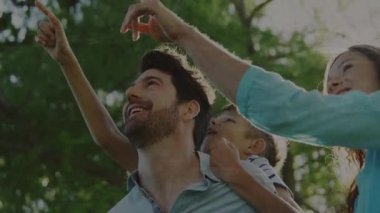 Arıza kullanarak pazarlama klibi, baba oğlunu taşırken ana rehber çocuk ağaç dalına uzanıyor. Aile, açık hava, doğa, neşeli, bağlanma, çocukluk, oyuncu