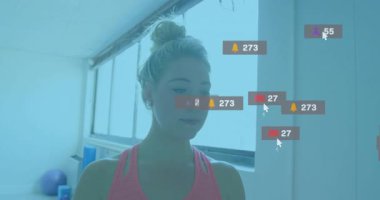 Spor salonunda spor yapan kadın pozu veriyor ve sosyal bildirimleri takip ediyor sonra da kayboluyor. Fitness, farkındalık, dijital, modern, sağlık, dinginlik, teknoloji