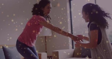 Anne elini uzatıyor ve kızını oturma odasındaki kanepede dans etmesi için yönlendiriyor. Dans, aile, sevgi, neşeli, gündelik, neşeli, bağ