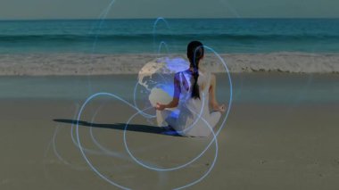 Sahilde meditasyon yapan bir kadın dijital enerji hatları kuruyor ve sağlık için dönen küreye dokuyor. Ruhanilik, sükunet, dinginlik, farkındalık, teknoloji, yenilik, refah