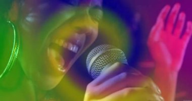 Mikrofonu dudaklara götüren müzik sanatçısı, renk nabzı kapladıkça yüksek notalar için vokalleri yoğunlaştırıyor. Performans, konser, sahne, ışıklandırma, duygu, sanatçılık, stüdyo