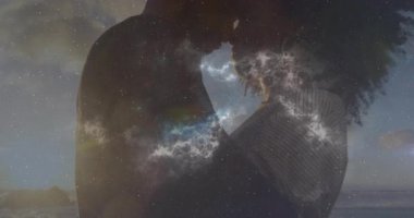 Çift, kayalık sahil dalgalarının gözlerinin içine bakarak teknolojik romantizmi gösteren dönen nebulaya neden oluyor. Romantizm, samimiyet, kozmik, göksel, siluet, günbatımı, aşk