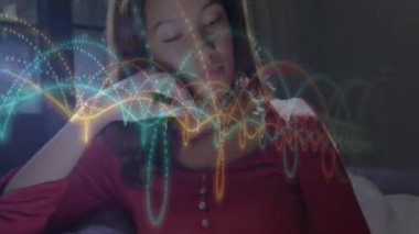 Kanepede oturan kadın, sağlık teknolojisi dalgalanması grafiklerine tepki veriyor soluyor, elini kaldırıyor, dinleniyor. Rahatlama, farkındalık, dijital sanat, dinginlik, refah, rahatlık, sükunet