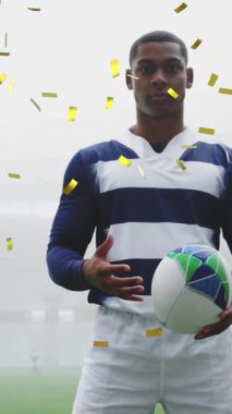 Erkek rugby oyuncusunun üzerine düşen altın konfetilerin animasyonu. Kameraya bakıyor, arka planda bir rugby topu tutuyor.