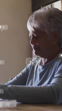 Sosyal medya simgelerinin animasyonu ve akıllı telefon kullanan yaşlı kadın üzerindeki afişler. küresel ağ, sosyal medya, teknoloji ve dijital arayüz kavramı dijital olarak oluşturulmuş video.