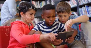 Üç çocuk tableti tıklatıyor ve kütüphanede öğrenmek için yüzen matematik formülleri geliştiriyor. Eğitim, işbirliği, fütüristik, teknoloji, okur yazarlık, keşif, etkileşim