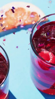 Konfeti düşüşünün animasyonu ve mavi arka planda kokteyller. Parti, içki, eğlence ve kutlama konsepti dijital olarak oluşturulmuş video.