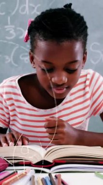 Okul çocuğunun üzerinde yüzen matematik denklemlerinin animasyonu masada oturup kitap okuyor. Okul kavramına geri dönüş dijital olarak oluşturulan imaj.